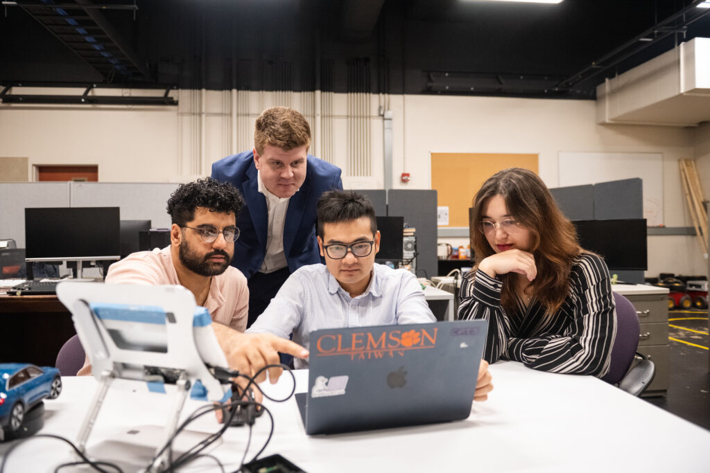 Mert Pesé (standing) works with members of his research team (sitting, from left) Pedram MohajerAnsari, Yu-Wei (Sam) Liu and Anna Galeano.
